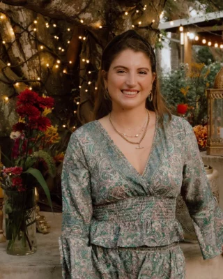 Phillipa Hill,of Phill’s Food Catering, smiling at an outdoor event decorated with fairy lights and flowers.